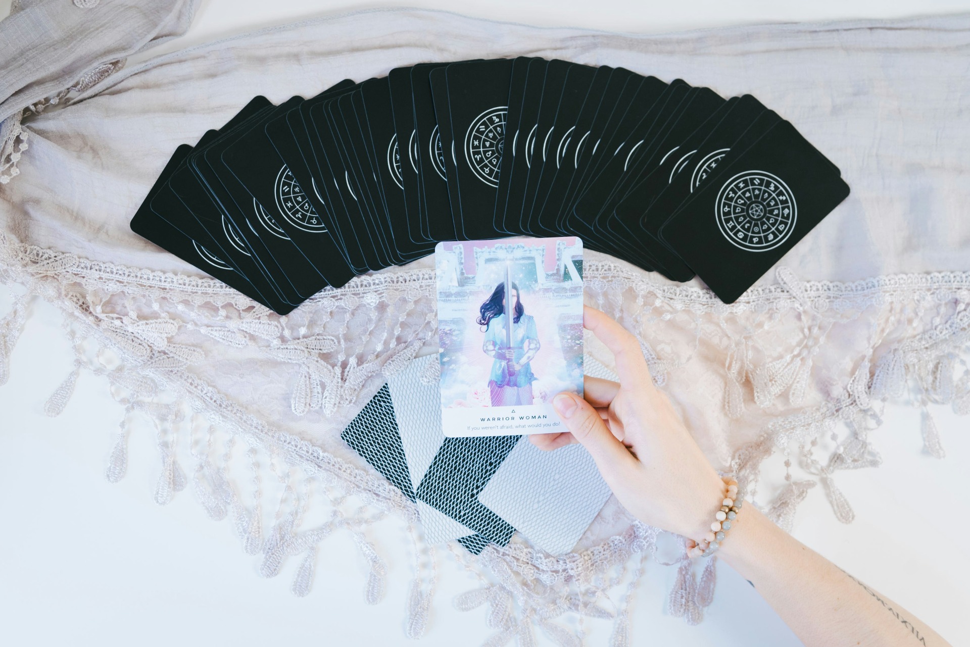 “Lectura de tarot con cartas esotéricas y la carta ‘Warrior Woman’, representando empoderamiento y guía espiritual”.